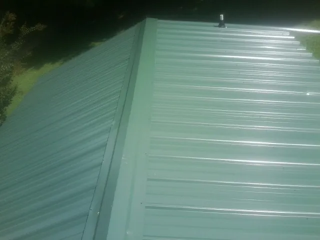 New green metal panels meeting at the ridge of a roof — Flat Roof Repair work by our crew in Rio Vista